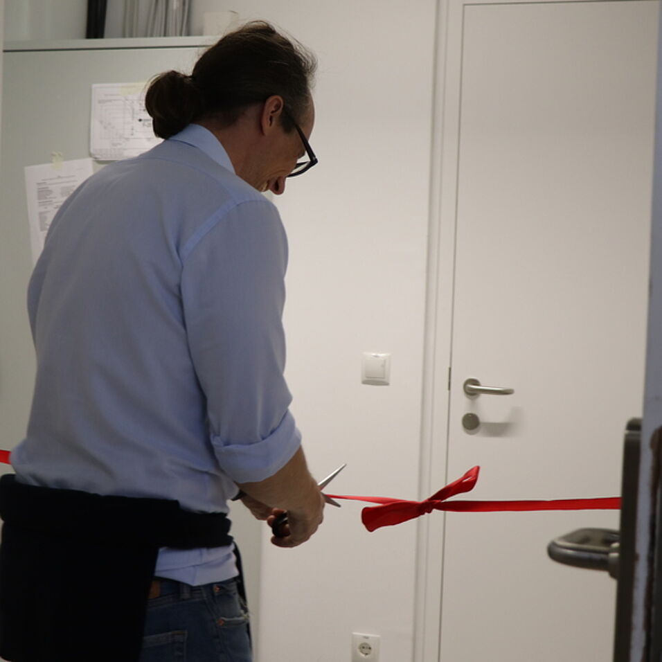 Prof. Heckl cutting the red ribbon in front of the new lab.